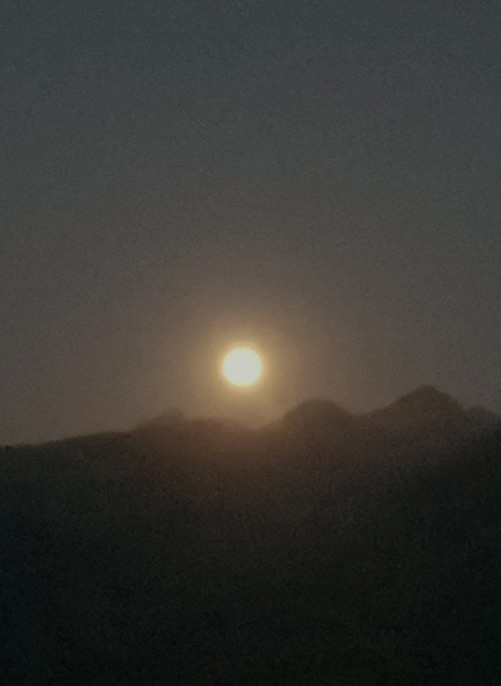 Mond über einer dunklen Bergsilhouette am nächtlichen Himmel